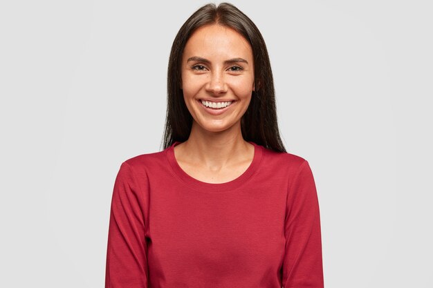 Foto di donna bruna soddisfatta con i capelli scuri, ha un sorriso piacevole