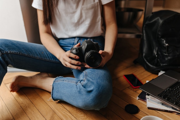 Foto di donna in jeans, seduta sul pavimento con parte anteriore, laptop e telefono