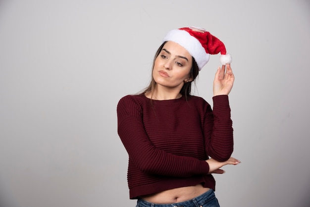 Foto di donna pensierosa in cappello di Natale che guarda lontano.