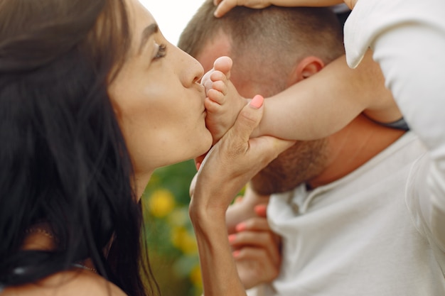 Foto di famiglia felice. Genitori e figlia. Famiglia insieme nel campo di girasoli. Uomo in camicia bianca.