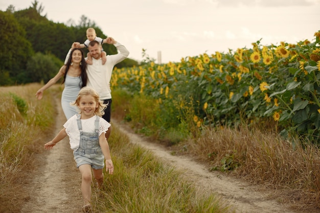 Foto di famiglia felice. Genitori e figlia. Famiglia insieme nel campo di girasoli. Uomo in camicia bianca.