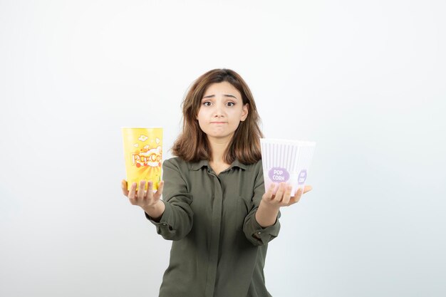 Foto di giovane donna in abito casual con scatole di popcorn in piedi. Foto di alta qualità