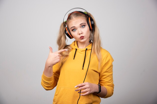 Foto di giovane donna in posa e ascolto di musica con le cuffie.