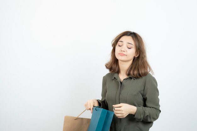 Foto di giovane ragazza stanca che tiene i sacchetti della spesa su bianco. Foto di alta qualità