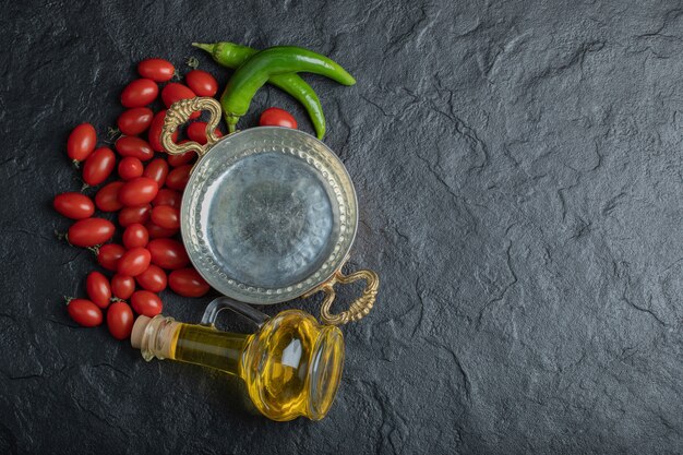 Foto di pomodorini, padella di peperone verde e bottiglia di olio. Foto di alta qualità