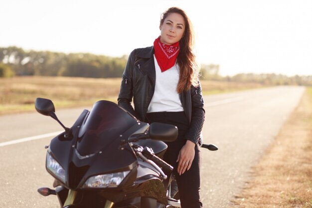 Foto di spensierata motociclista vestita in abiti alla moda