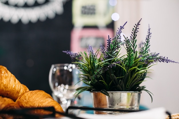 Foto di stock di fiori di lavanda freschi in acciaio argento pentola accanto a croissant appena sfornati.