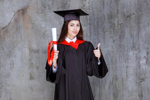 Foto di studentessa con certificato di laurea che dà i pollici in su. Foto di alta qualità