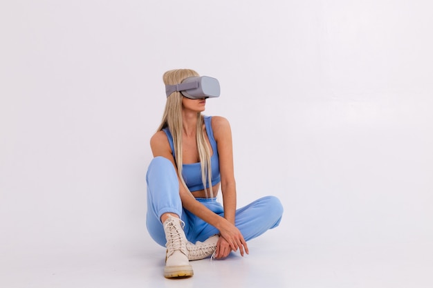 Foto di studio di una giovane donna attraente in un caldo abito blu alla moda che indossa occhiali per realtà virtuale