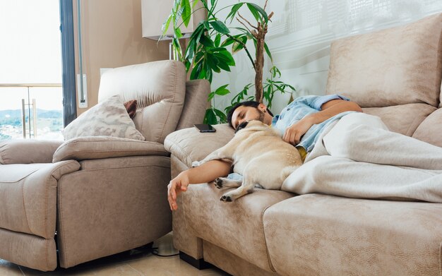 Foto di un bell'uomo ispanico che dorme su un divano con il suo cane