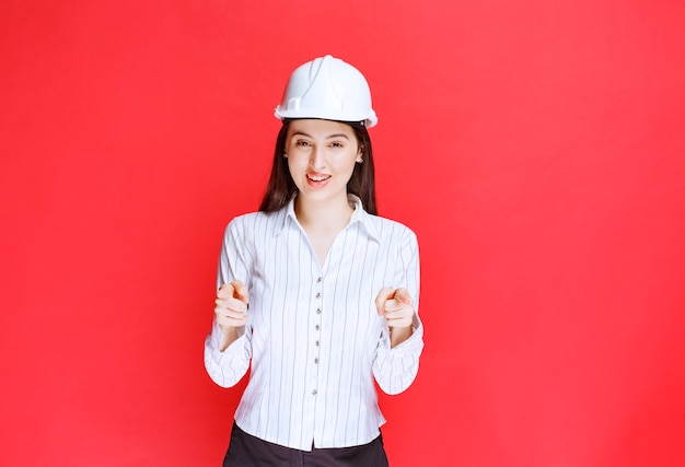 Foto di una bella donna d'affari che indossa un cappello di sicurezza che indica.