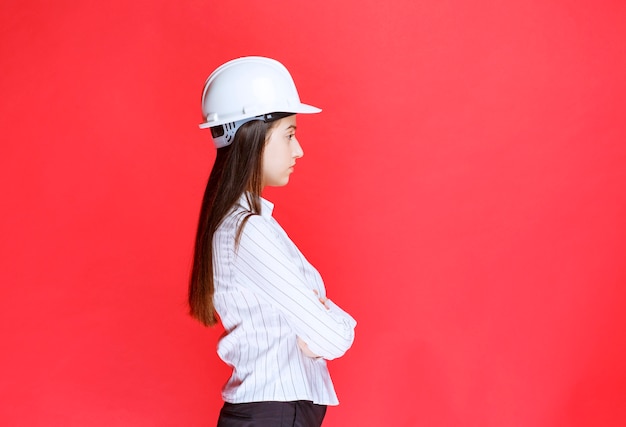 Foto di una bella donna d'affari che indossa un cappello di sicurezza in piedi con le braccia incrociate.