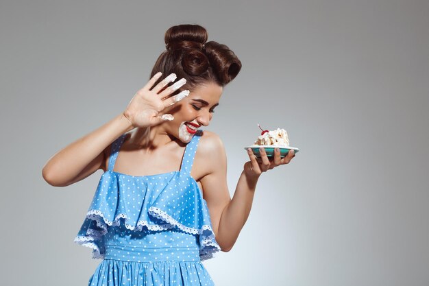 Foto di una bella donna pin-up che mangia la torta allo studio