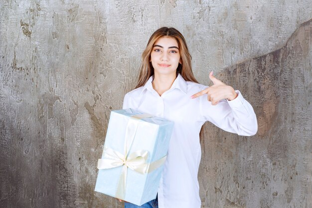 Foto di una bella modella con i capelli lunghi che indica un grande regalo