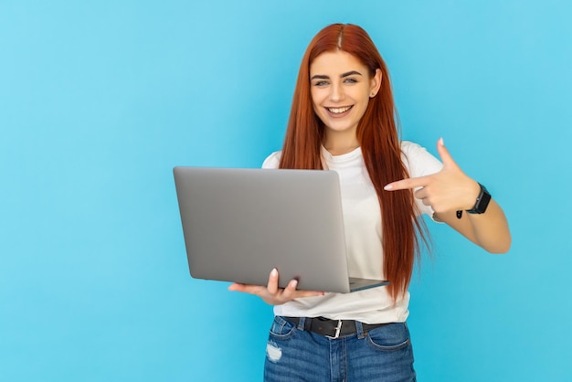 Foto di una donna divertente dai capelli rossi che guarda il laptop su blu