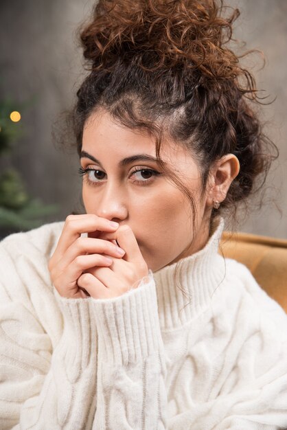 Foto di una giovane donna seduta su una sedia comoda vicino all'albero di Natale