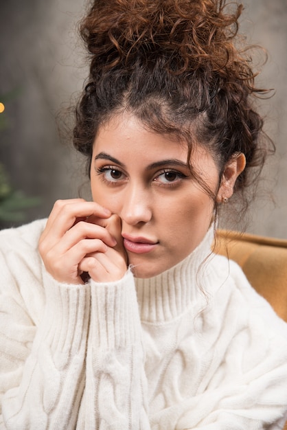 Foto di una giovane donna seduta su una sedia comoda vicino all'albero di Natale