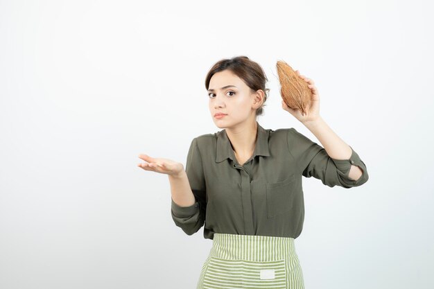 Foto di una giovane ragazza che tiene una noce di cocco pelosa su bianco. Foto di alta qualità