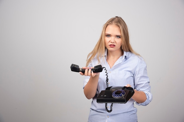 Foto di una modella arrabbiata in piedi e con in mano un vecchio ricevitore nero