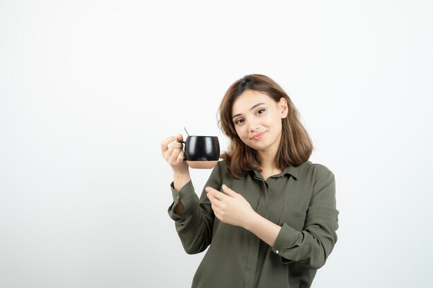 Foto di una ragazza adorabile che tiene una tazza di caffè caldo. Foto di alta qualità