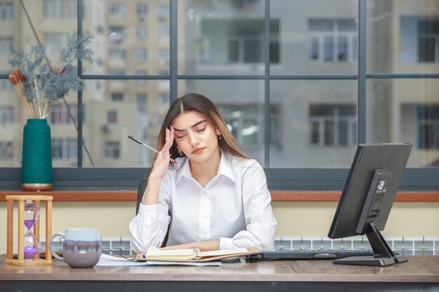 Foto di una ragazza seduta alla scrivania che si sente stanca