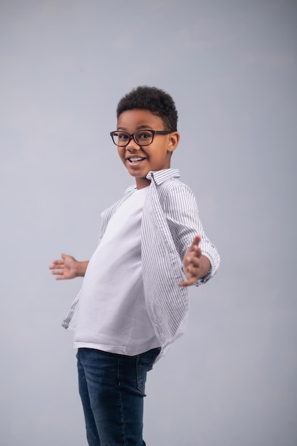 Foto in studio di un simpatico ragazzo emotivo con le braccia allargate ai lati in posa per la fotocamera