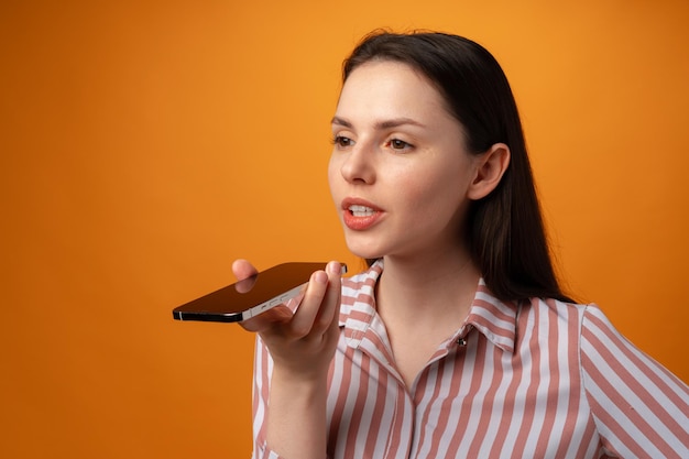 Foto in studio di una giovane donna che parla al telefono su sfondo giallo