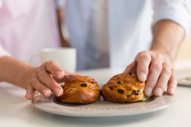 Foto potata della famiglia amorosa matura delle coppie che mangia le pasticcerie.