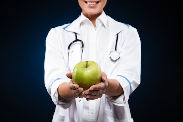 Foto potata della giovane donna in abito medico che tiene mela verde