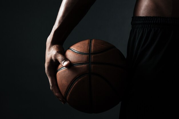Foto potata della palla della tenuta del giocatore di pallacanestro