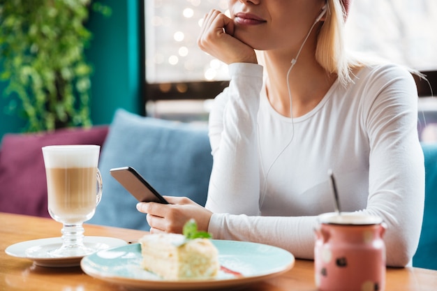 Foto potata di musica d'ascolto della giovane signora in caffè.