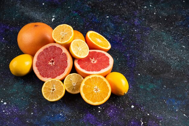 Foto ravvicinata di fette di pompelmo e limone tagliate a metà sul tavolo scuro.