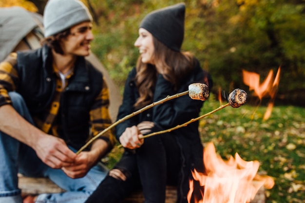 Foto ravvicinata di marshmallow arrostiti sul fuoco vicino alla tenda in campeggio