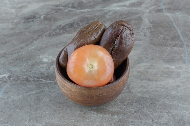 Foto ravvicinata di pomodori sottaceto e melanzane in una ciotola di legno.