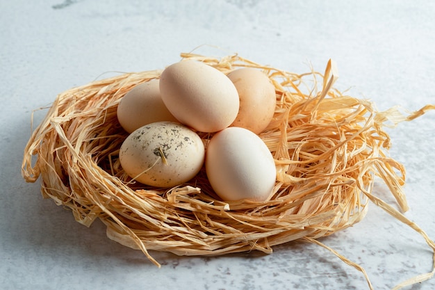 Foto ravvicinata di uova di gallina organiche fresche sulla paglia.