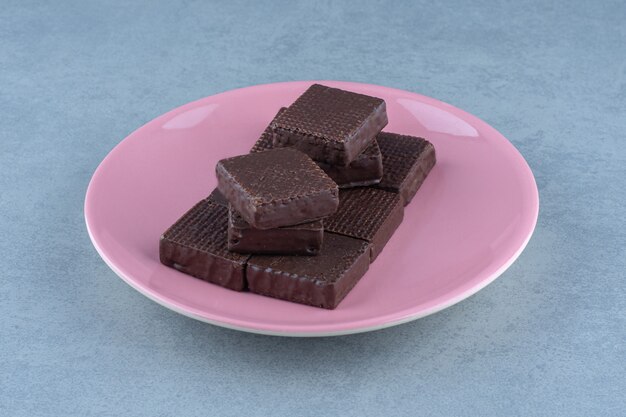 Foto ravvicinata di wafer al cioccolato su piastra rosa.