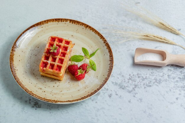 Foto ravvicinata di waffle fatti in casa con lamponi freschi.