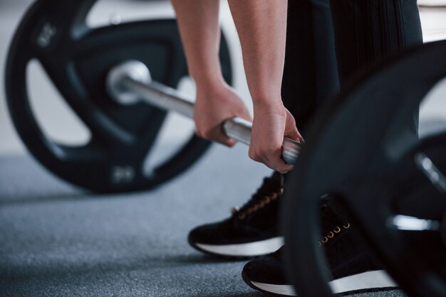 Foto ritagliata di donna che fa squat con bilanciere in palestra