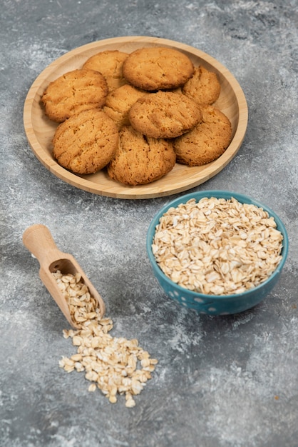 Foto verticale di farina d'avena in una ciotola davanti a biscotti fatti in casa.