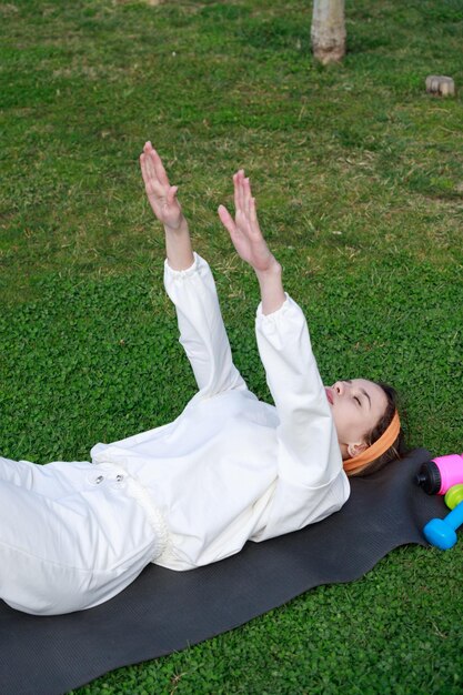 Foto verticale di una giovane ragazza sdraiata sul tappetino da yoga e alzata le braccia Foto di alta qualità