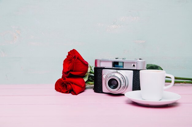 Fotocamera accanto a caffè e rose