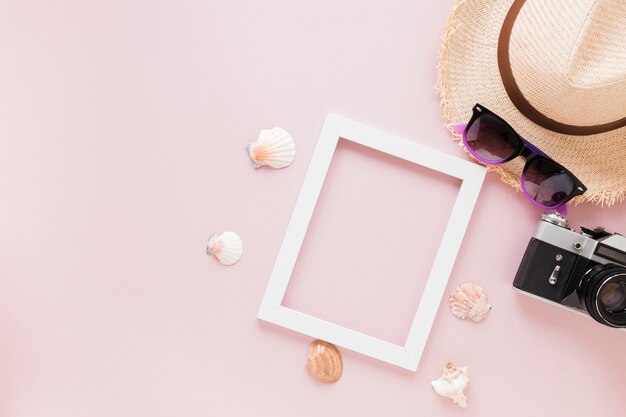 Fotocamera con cappello di paglia, conchiglie e cornice