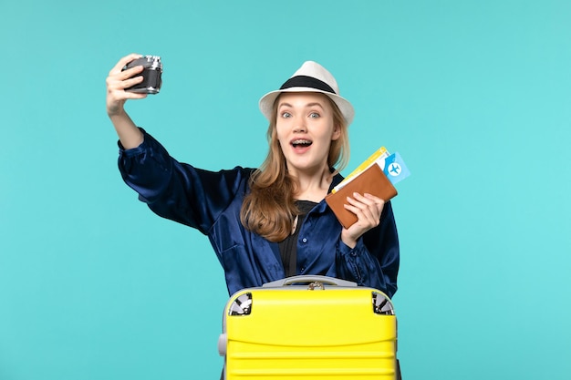 Fotocamera e biglietti della tenuta della giovane donna di vista frontale sul viaggio aereo di viaggio di viaggio del mare dello scrittorio blu