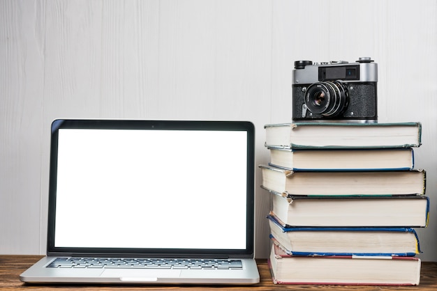 Fotocamera e libri vicino al computer portatile