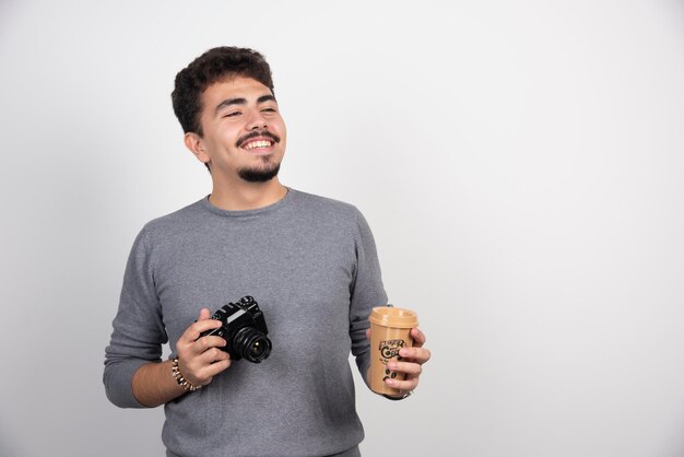 Fotografa tenendo in mano una tazza di caffè in plastica per scattare foto.