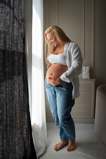 Fotografia completa di una donna incinta che trascorre del tempo in casa