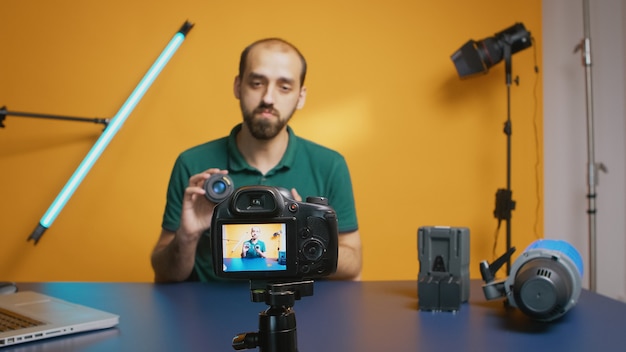 Fotografo che parla delle specifiche dell'obiettivo durante la registrazione dell'episodio del vlog per gli abbonati. Tecnologia dell'obiettivo della fotocamera registrazione digitale creatore di contenuti influencer social media, studio professionale per po