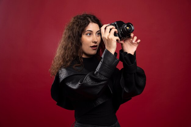 Fotografo di donna in abito tutto nero che scatta foto con una macchina fotografica.