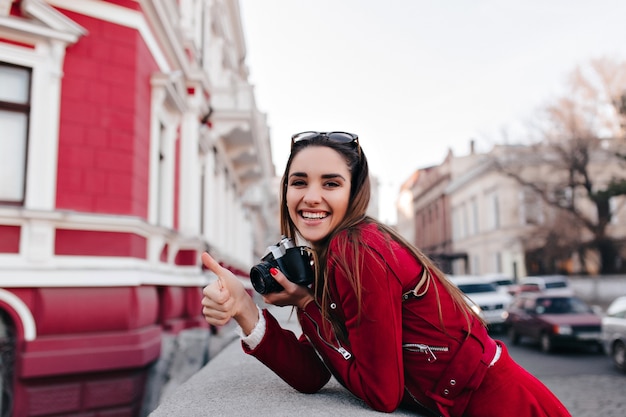 Fotografo femminile entusiasta con il manicure rosso che si rilassa nel fine settimana