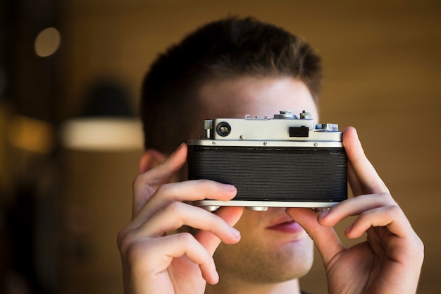 Fotografo maschio che cattura maschera con macchina fotografica d&#39;epoca